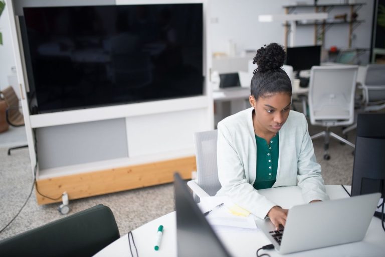 Profissional trabalha em um laptop em um escritório moderno.