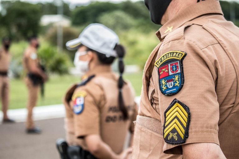 Policiais uniformizados permanecem em formação em uma área externa.